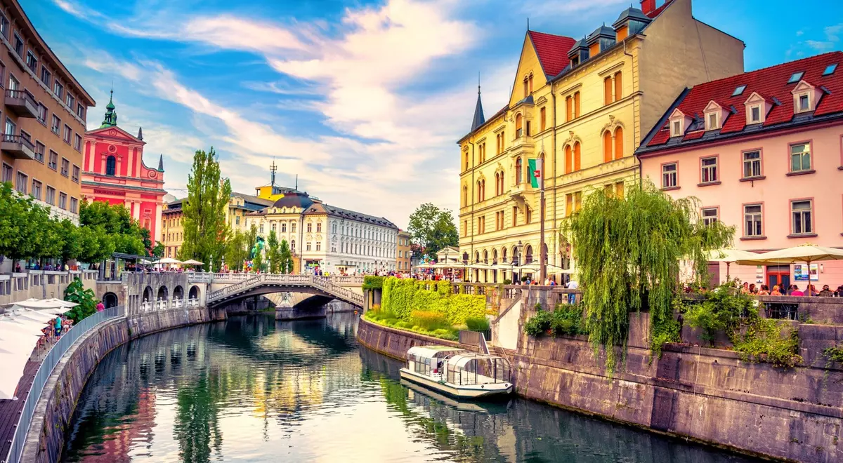 The Ljubljanica river in central Ljubljana with the pink Franciscan Church and riverside cafes